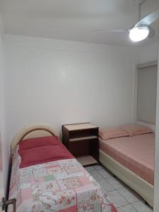 a bedroom with two beds and a night stand at Espaço Aconchegante no coração da Praia da Enseada in Guarujá
