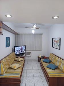 a living room with two couches and a flat screen tv at Espaço Aconchegante no coração da Praia da Enseada in Guarujá