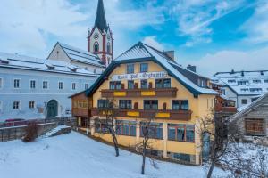 żółty budynek z wieżą zegarową w śniegu w obiekcie Örglwirt Ferienwelt - Hotel Post Örglwirt w mieście Mariapfarr