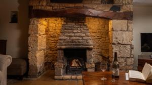 a stone fireplace in a living room with wine glasses on a table at Wyck Cottage in Bourton on the Water