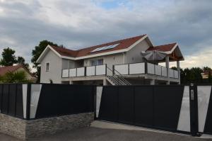 a house with a black gate in front of it at Appartement de 70 m2 dans maison comptenporaine in Charnècles