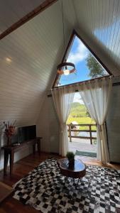 a living room with a large window and a table at Cabanas Bela Vista in Rolante