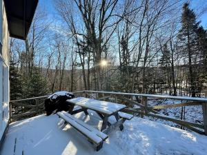 a picnic table on the deck of a house in the snow at Cozy Chalet at Jay Peak in Montgomery Center