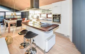 a kitchen with white cabinets and a counter with stools at Holiday Home Øster Kjulvej Denmk Ii in Hirtshals