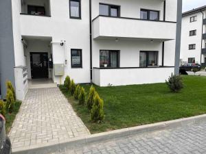 a white building with a grass yard in front of it at Malina Residence Aparthotel in Cisnădie