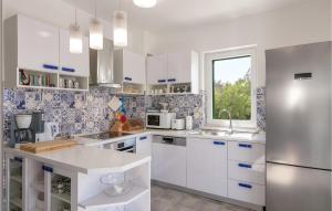 a kitchen with white cabinets and a window at Villa Makarac in Milna
