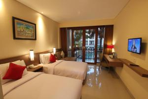 a hotel room with two beds and a desk at Grand La Walon Hotel in Legian