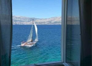 a sail boat in the water through a window at Apartments Sova in Postira