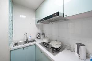 a white kitchen with a sink and a stove at Shanghai Hills & Serendipity Springtime Family BNB with Two Rooms close to West Nanjing Rd in Shanghai