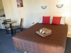 a large brown bed with red pillows and a table at Narrabri Motel and Caravan Park in Narrabri