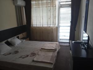 a bedroom with a bed and a window with curtains at Къща за гости in Primorsko