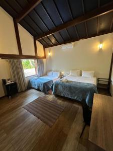 a bedroom with two beds and a wooden floor at Gaia Hotelaria in Teresópolis