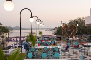 a patio with tables and chairs with a view of the water at Hide-In Udaipur - A Lake View Boutique Hotel in Udaipur