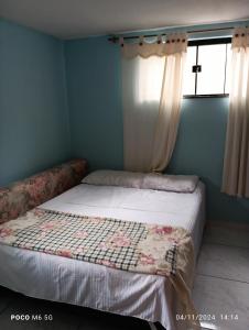 a bedroom with a bed with a quilt on it at Casa confortavel in Ponta Grossa