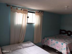 a bedroom with a bed and a window with curtains at Casa confortavel in Ponta Grossa