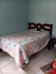 a bed with a pink and blue blanket on it at Casa confortavel in Ponta Grossa