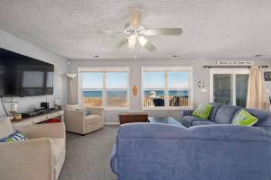 a living room with a blue couch and a ceiling fan at OBX 4BR Oceanfront Cottage in Kill Devil Hills
