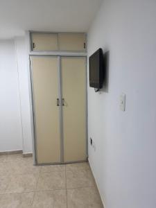 Una habitación con una puerta con un televisor en la pared. en Acogedor Apartaestudio cerca al centro Armenia 3, en Armenia 4 fotos más