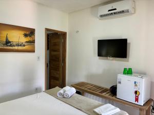 a room with a bed and a tv on the wall at Pousada Vila Tapera in Barra Grande