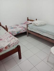 three beds in a room with a white tiled floor at Casa pousada Milton in Angra dos Reis