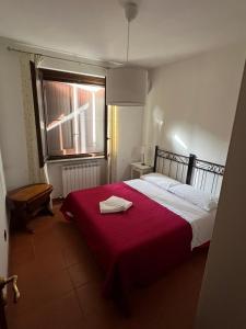 a bedroom with a bed with a red blanket and a window at Casa Pruno Rosso in Montemerano