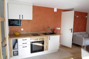 una piccola cucina con armadi bianchi e lavandino di Studio avec jardin Centre ville a Remiremont Altre 10 foto