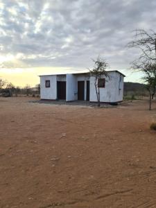 a white building in the middle of a field at Ansta Farmhouse Self Catering Camping Nursery in Outjo +49 photos