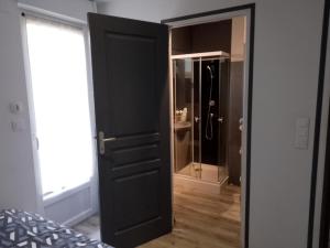 a black door leading to a bathroom with a shower at Un Appartement tout à vous in Carhaix-Plouguer +2 photos