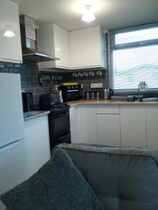 a kitchen with white cabinets and a couch in it at The Marylyn in Mablethorpe