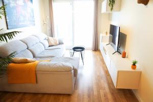 a living room with a white couch and a tv at El Toro Apartments in Altea