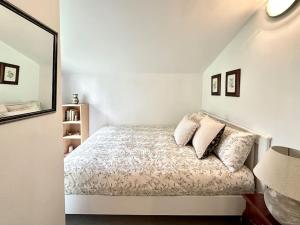 Un dormitorio con una cama con almohadas y un espejo. en As Barrocas, en Nigrán