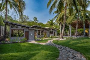 een huis met palmbomen voor een tuin bij Riptide Lodge El paredon Guatemala in El Paredón Buena Vista