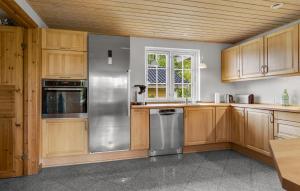 a kitchen with wooden cabinets and a stainless steel refrigerator at Pet Friendly Home In Ebeltoft With Wifi in Ebeltoft