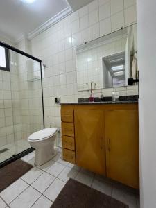 a bathroom with a toilet and a sink and a mirror at O PARAÍSO É AQUI! Apto muito próximo a praia in Guarapari