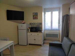 a living room with a refrigerator and a television at Studio 2 - Mont Dore face aux Thermes - Hyper-Centre in Le Mont-Dore