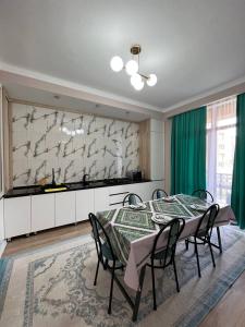 a dining room with a table and some green curtains at Жан Айсулу in Türkistan