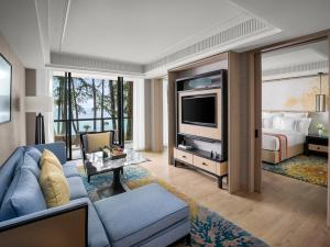 a living room with a blue couch and a bed at InterContinental Phuket Resort by IHG in Kamala Beach