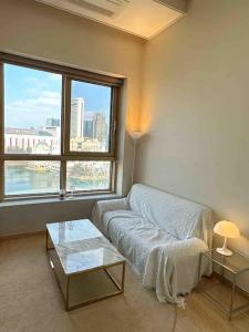 Una sala de estar con un sofá y una ventana grande. en Comfortable Duplex House with City Lake View #SeokchonLakeView #LotteWorld, en Seúl