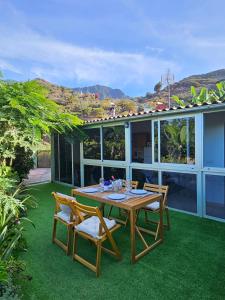 a wooden table and chairs on a patio with grass at Casa Erika in Hermigua