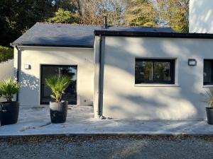 a white building with two plants in front of it at maison rue neuve in Plouay