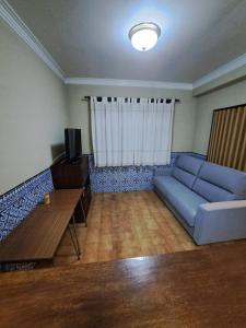 a living room with a blue couch and a table at Apart Praia da Costa da Caparica in Costa da Caparica +3 photos