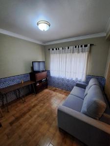 a living room with a couch and a television at Apart Praia da Costa da Caparica in Costa da Caparica