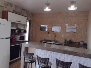a kitchen with a counter with chairs and a refrigerator at Alexandre's house in Piranhas