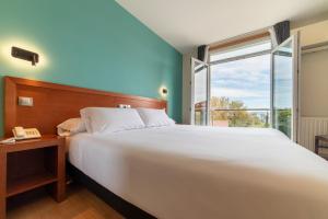 Un dormitorio con una gran cama blanca y una ventana. en Hotel Playa Langosteira by Adeloló, en Finisterre