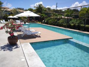 a swimming pool with two chairs and an umbrella at Apartamento térreo a 300 metros da praia de Itacimirim com piscina e jardim in Itacimirim