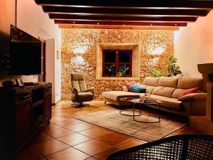a living room with a couch and a stone wall at Finca Reina de la isla in Felanitx