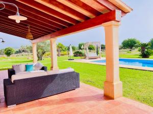a covered patio with a couch and a pool at Finca Reina de la isla in Felanitx