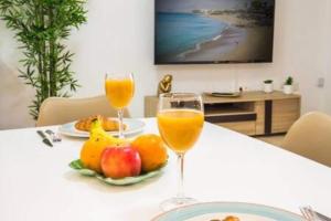 two glasses of orange juice and fruit on a table at Apartamento Luna in Tías