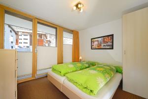 ein Schlafzimmer mit einem Bett mit grünen Kissen und einem Fenster in der Unterkunft Ferienwohnung Haus Achilles in Zermatt
