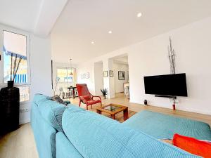 a living room with a blue couch and a tv at Casa Blanca sea view in Santa Pola
